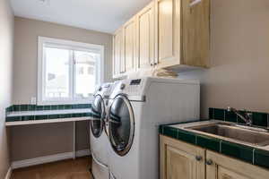 Washroom featuring cabinet space, baseboards, independent washer and dryer, carpet flooring, and a sink