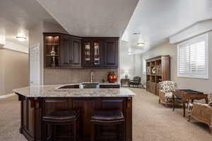 Bar featuring a textured ceiling, decorative backsplash, and light colored carpet