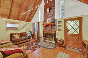 Living area featuring a fireplace, wood ceiling, wood finished floors, high vaulted ceiling, and beamed ceiling