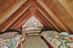 Carpeted bedroom with wood ceiling and lofted ceiling with beams