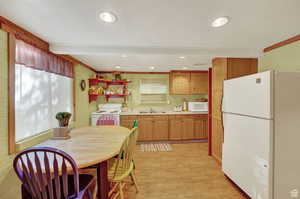 Kitchen with recessed lighting, light countertops, light wood-style floors, a sink, and white appliances