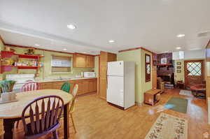 Kitchen with white appliances, light wood-style flooring, visible vents, and a sink