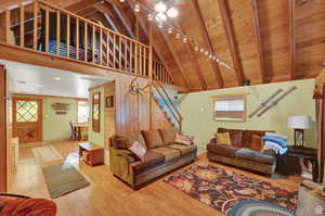 Living room featuring wooden ceiling, wood finished floors, stairs, high vaulted ceiling, and beam ceiling