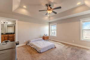 Bedroom featuring baseboards, a tray ceiling, recessed lighting, and light colored carpet