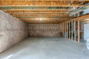 Unfinished basement with freestanding refrigerator