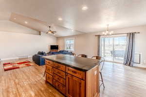 Kitchen featuring dark countertops, plenty of natural light, lofted ceiling, and a kitchen bar