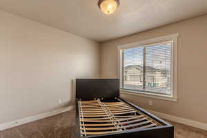 Bedroom featuring a textured ceiling, carpet, and baseboards