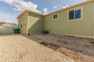 View of side of home featuring a gate, fence, cooling unit, and stucco siding