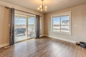 Empty room featuring a healthy amount of sunlight, baseboards, a chandelier, and wood finished floors