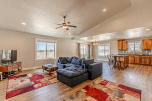 Living room with lofted ceiling, light wood-style floors, baseboards, and a textured ceiling