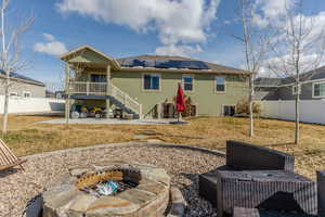 Back of house with solar panels, a patio area, a fenced backyard, and stucco siding