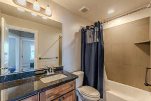 Full bathroom with visible vents, vanity, toilet, and shower / bath combo with shower curtain