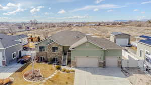 View of front of home with an attached garage, stone siding, a gate, and fence private yard