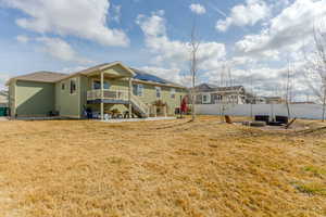 Back of property featuring a fire pit, fence, a yard, stairway, and stucco siding