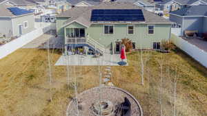 Rear view of property with roof mounted solar panels, a fenced backyard, a residential view, and a patio