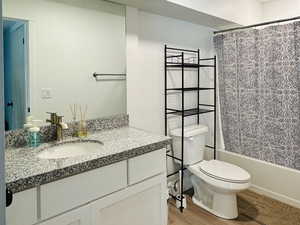 Bathroom featuring visible vents, toilet, shower / bath combo with shower curtain, vanity, and wood finished floors