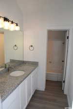 Full bathroom featuring washtub / shower combination, wood finished floors, vanity, and baseboards