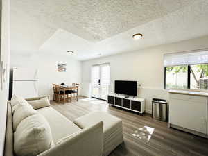 Living area with a textured ceiling, baseboards, and wood finished floors