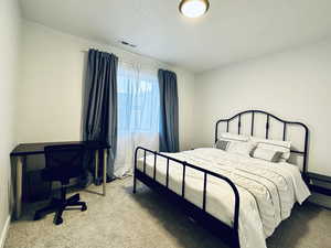 Carpeted bedroom featuring visible vents and a textured ceiling