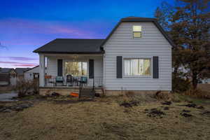 View of front of home with covered porch and a shingled roof