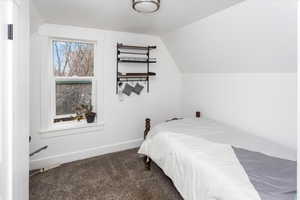 Carpeted bedroom with vaulted ceiling and baseboards