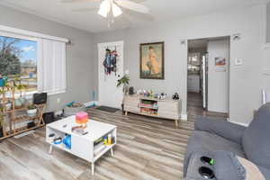 Living room with wood finished floors, a ceiling fan, and baseboards