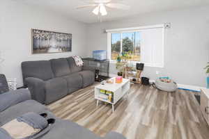 Living room featuring ceiling fan, baseboards, and wood finished floors