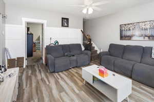 Living room featuring light wood-style flooring, stairway, and ceiling fan