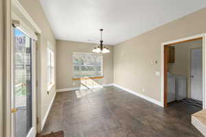 Interior space featuring baseboards, washing machine and clothes dryer, and a notable chandelier