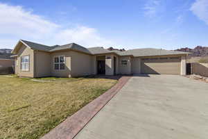 Ranch-style home featuring stucco siding, concrete driveway, a front yard, fence, and a garage