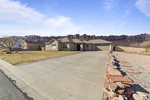 Single story home featuring a garage, concrete driveway, stucco siding, fence, and a front yard