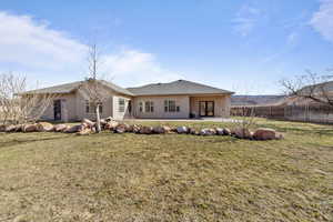 Rear view of house with a patio area, fence, a lawn, and stucco siding