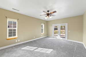 Carpeted empty room with ceiling fan, french doors, visible vents, and baseboards