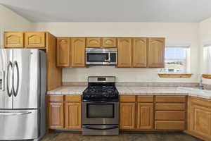 Kitchen featuring stainless steel appliances, a sink, and brown cabinets