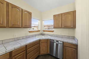 Kitchen with brown cabinets, a sink, and stainless steel dishwasher