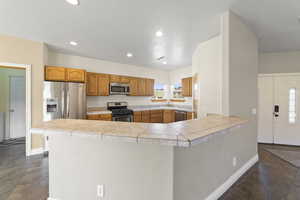 Kitchen with a peninsula, appliances with stainless steel finishes, light countertops, and a sink