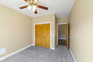 Unfurnished bedroom with carpet floors, a closet, a ceiling fan, and baseboards