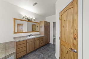 Bathroom featuring stone finish flooring, vanity, visible vents, and baseboards