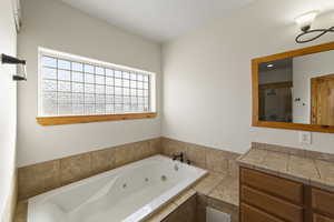 Bathroom featuring tiled shower, a jetted tub, and vanity