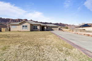 Single story home with stucco siding, an attached garage, a front yard, a mountain view, and fence