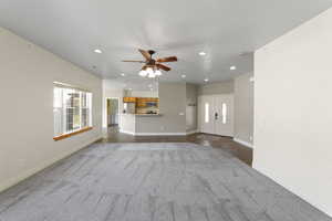 Unfurnished living room featuring recessed lighting, ceiling fan, baseboards, and dark colored carpet