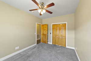 Unfurnished bedroom with carpet, baseboards, visible vents, and ceiling fan