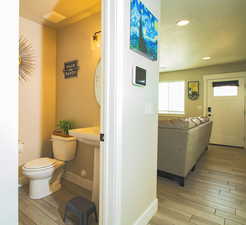 Corridor featuring light wood finished floors, baseboards, a textured ceiling, and recessed lighting