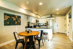 Dining room with a textured ceiling, recessed lighting, light wood-style flooring, and baseboards