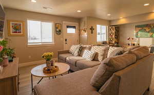 Living room featuring light wood-type flooring, plenty of natural light, visible vents, and recessed lighting