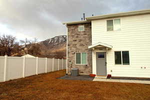 Front view of house featuring a yard, stone siding, and fence