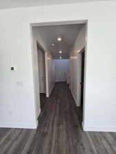 Hall with dark wood-type flooring and baseboards