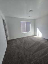 Spare room with a textured ceiling, baseboards, and carpet flooring