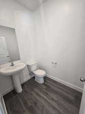 Bathroom with wood finished floors, toilet, and baseboards