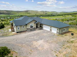 View of front facade featuring a mountain view, stone siding, stucco siding, and an attached garage